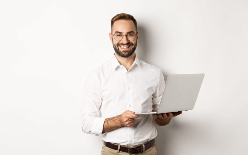 Business. Sucessful businessman working with laptop, using computer and smiling, standing over white background Business. Sucessful businessman working with laptop, using computer and smiling, standing over white background.