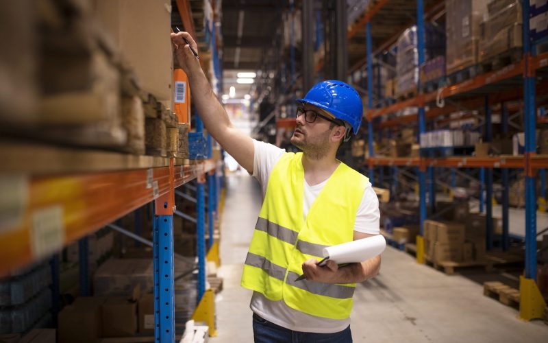Warehouse worker checking inventory in large distribution warehouse. Warehouse worker checking inventory in large distribution warehouse.